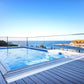 Daisy Below Ground Box Pool Cover Roller installed beside a modern swimming pool