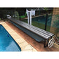 Daisy Under Bench Pool Cover Roller (Powered) in Charcoal Shimmer beside a modern swimming pool